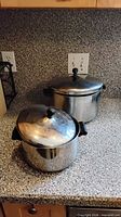 Both stainless steel pots with lids on kitchen counter