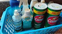 Blue basket with two Comet cleanser cans, Lemi Shine bottle, multiple spray cleaners and pump bottle