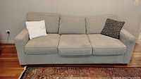 Front view of light gray three-seat sofa with cushions