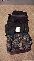 Stack of four bags showing floral tote, two black fabric bags and additional black item