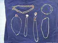 All six necklaces laid out showing overall styles and metal tones