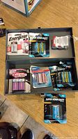 Toolbox open showing various packaged batteries sorted in trays