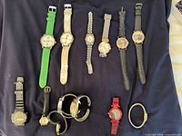 All 13 watches laid out on dark cloth showing band styles and colours