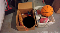 Cardboard box and crate containing assorted sports gear including basketballs, gloves, snorkel mask
