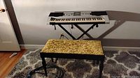 Keyboard on X stand with bench and power cable visible