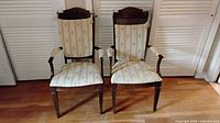 Front view of both armchairs showing upholstery, cane backs, wood finish