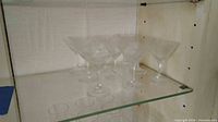 Set of six etched martini glasses on glass shelf
