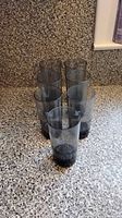 Six smoked grey tumblers arranged on countertop