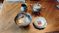 Group shot of silverplate bowl, creamer, lidded sugar, and stack of three porcelain leaf dishes