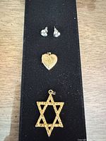 Overall view of pendant, locket, and earrings on display pad