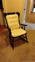 Front view of black wooden rocking chair with cream cushions