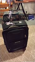 Two suitcases stacked, black in front, floral behind