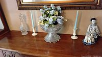 Bowl on pedestal, candles and figurine visible
