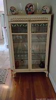 Front view of cream French Provincial china cabinet with glass doors and shelves