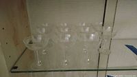 Ten clear glass etched coupes on glass shelf