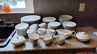 Full assortment of plates, bowls, cups and serving pieces on counter