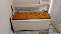Front view of white storage bench with mustard cushion
