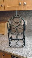 Green metal six-bottle wine rack on countertop