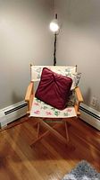Director chair with burgundy and floral pillows displayed