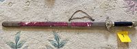 Full view of sword in scabbard showing hanging chain and wear on scabbard