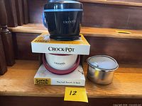 Black Crock-Pot Lunch Crock food warmer on product box with stainless container beside