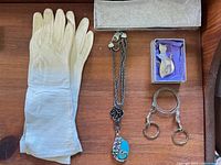 Overview of gloves, necklace, brooch in box and wire lanyard