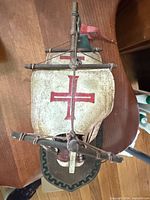 Top view of wooden ship model showing sail with red cross and rigging