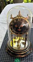 Full view of clock under glass dome on painted wood base