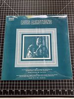 Front teal album cover with photo of Louis Armstrong and SagaPan logo