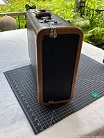 Suitcase end view showing brown leather trim and metal latch