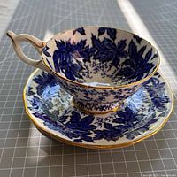 Teacup resting on saucer showing exterior pattern and gold trim