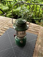 Full view of green Coleman lantern with handle