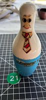 Full view of bowling pin piggy bank front showing face and tie