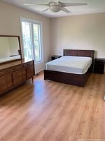 Bedroom view showing bed frame, mattress, nightstand, dresser with mirror