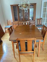 Dining table with six chairs and hutch in background