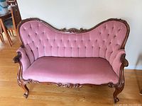 Front view of pink tufted Victorian loveseat showing carved wood frame and upholstery