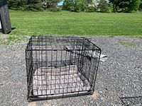 Open black wire crate with cushion inside, outdoor setting