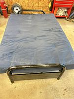 Full view of black metal frame with blue mattress
