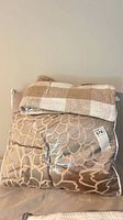 Comforter set in clear bag with plaid blanket folded on top