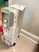 Front three-quarter view of heater showing fins, control panel, casters, power cord