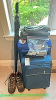 Two blue suitcases stacked, umbrella, hiking shoes, packing cubes on top