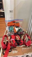 Group view of red ratchet straps, orange strap, and bag of bungee cords