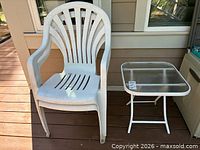 White plastic patio chair beside white metal glass-top folding table