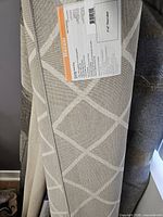 Rolled rug showing geometric design and attached label