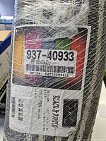 Rolled area rug wrapped in plastic with shipping and product labels visible