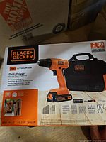 Front of sealed retail box showing drill, accessories and carry bag
