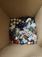 Box containing assorted ornaments blue, gold, plush animals, wooden house, over 50 pieces
