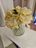 Top angled view showing yellow and white faux flowers and cut-glass vase