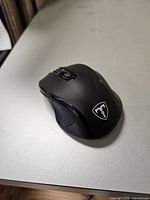 Top view of black wireless mouse showing shield logo and scroll wheel