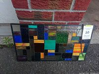 front view of stained glass panel showing multicolor geometric design and chain